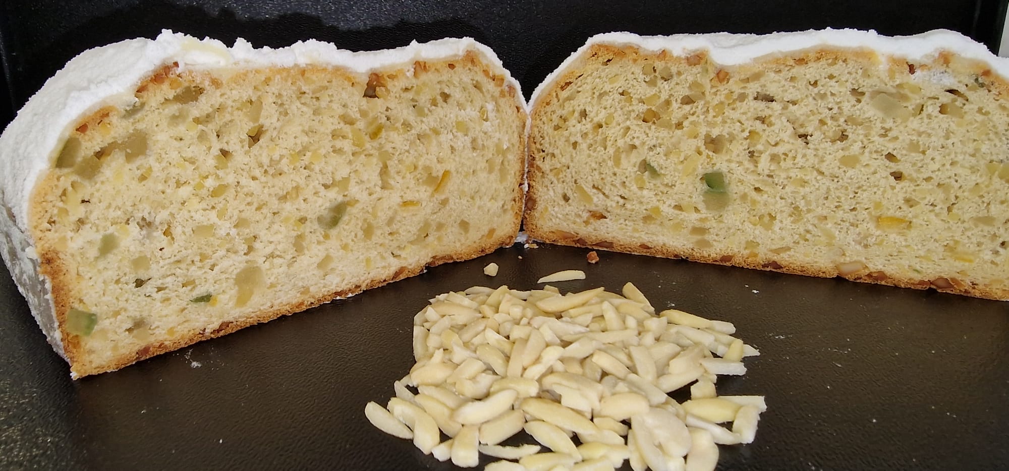 Unser Mandelstollen mit seinen Mandeln im Vordergrund auf einem Häufchen - Der Link auf diesem Bild öffnet das Produkt einzeln.