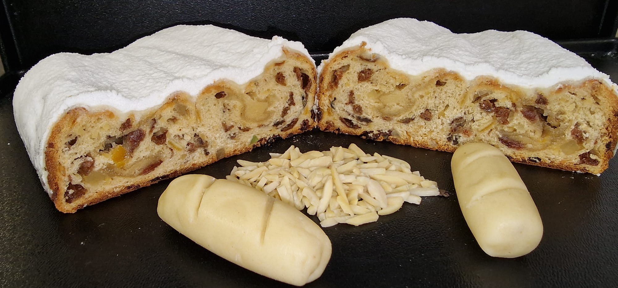 Unser Marzipanstollen mit seinen Zutaten im Vordergrund - Das Bild öffnet das Produkt einzeln.